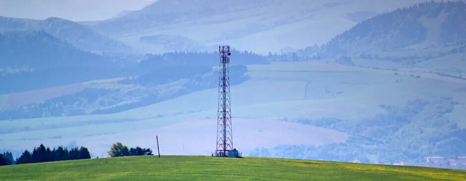 Mobilfunkmast auf einem Höhenzug vor bewaldeter Landschaft